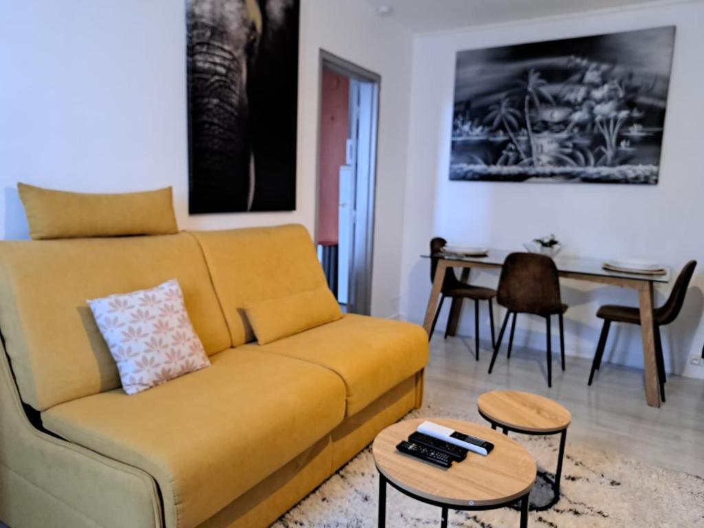Una sala de estar con un sofá amarillo y una mesa. en Studio Nimes - Clim - Wifi -Cuisine privatif - parking privé - salle de bain commune- balcon, en Nimes