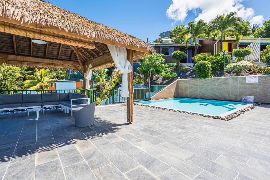 Un patio con una sombrilla de paja y una piscina. en Villasticreole, en Deshaies