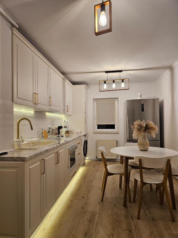 a kitchen with a table and a refrigerator at White Central Apartment in Bistriţa