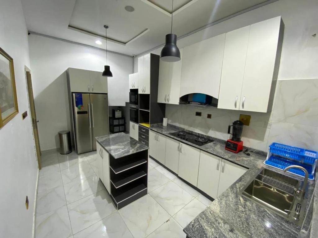 Una cocina con gabinetes blancos y electrodomésticos de acero inoxidable. en Beautiful peaceful comfortable, en Lekki