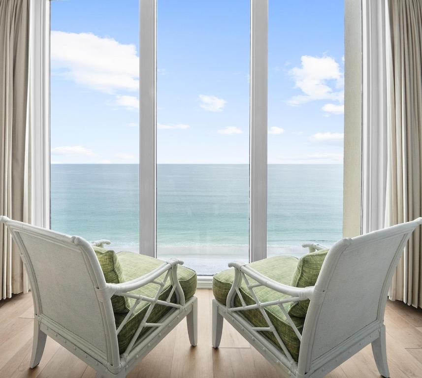 twee stoelen voor een groot raam met uitzicht op de oceaan bij Mermaid Manor in Navarre