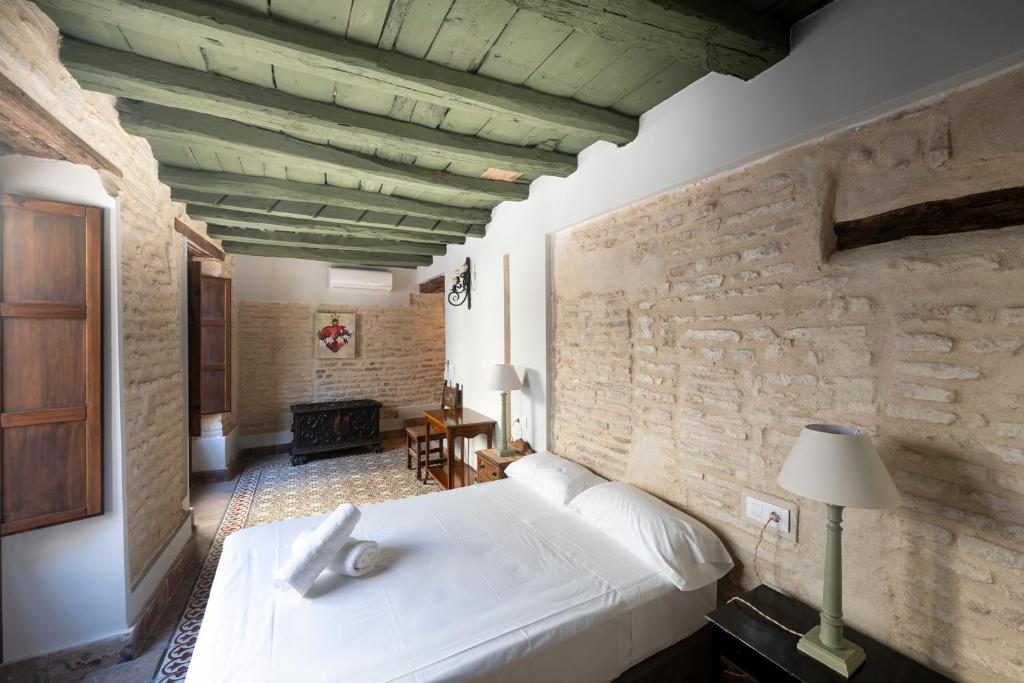 a bedroom with a white bed and a stone wall at Hospedería Monasterio de San Leandro in Seville