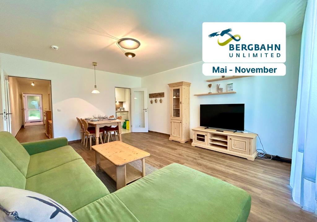 a living room with a green couch and a television at Waldgeflüster, Montana Haus in Oberstdorf