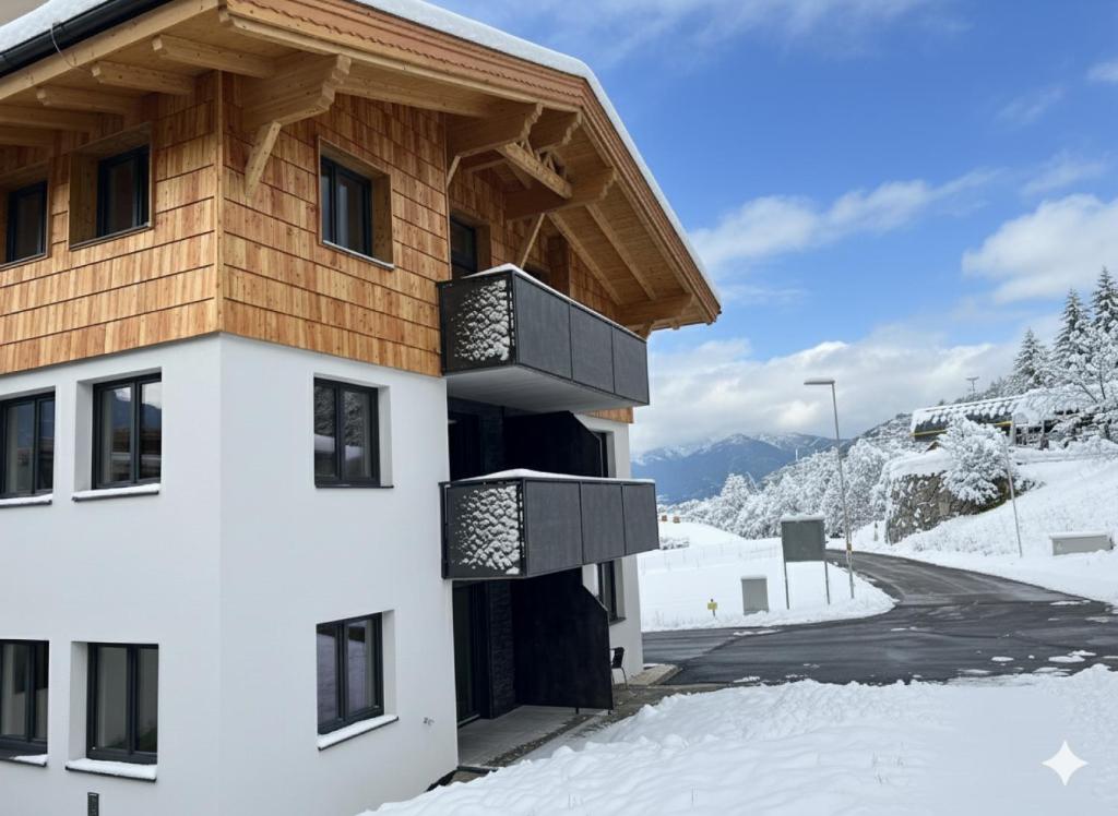 a building with a balcony in the snow at Studler-Eck in Oberperfuss