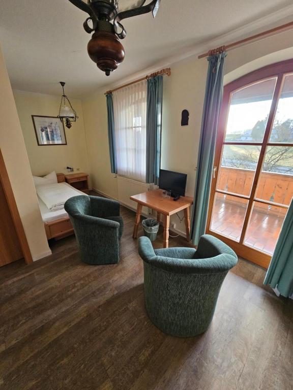 a room with two chairs and a bed and a table at Braukeller Fattigau in Oberkotzau