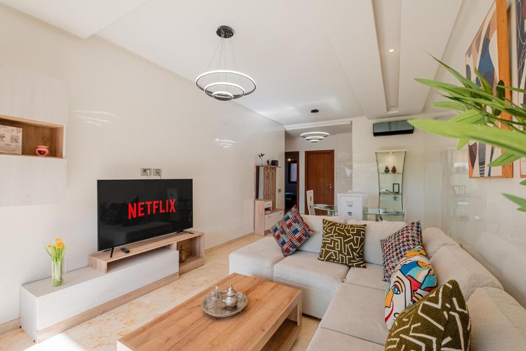 un salon avec un canapé et une télévision dans l'établissement Appartement de prestige au golf, à Marrakech
