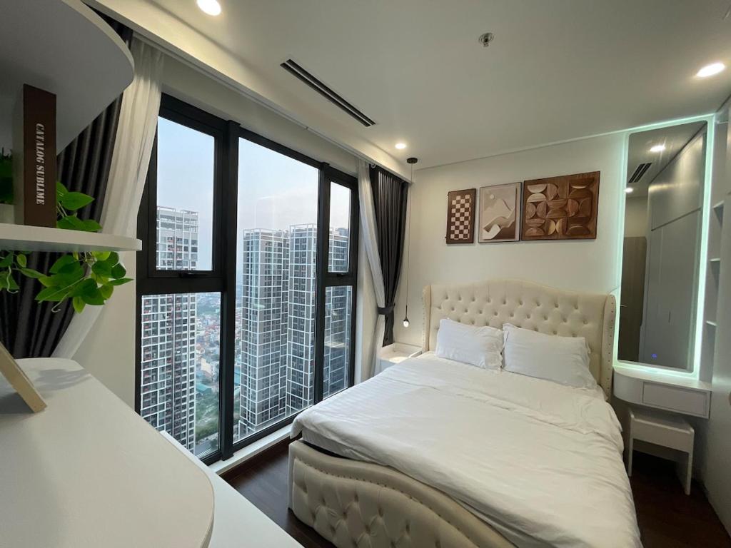 a bedroom with a white bed and large windows at Hommit - Căn hộ View Bể Bơi 3 Phòng ngủ, 2 vệ sinh - Tòa Masteri A, Vinhomes Smart City in Phú Thú