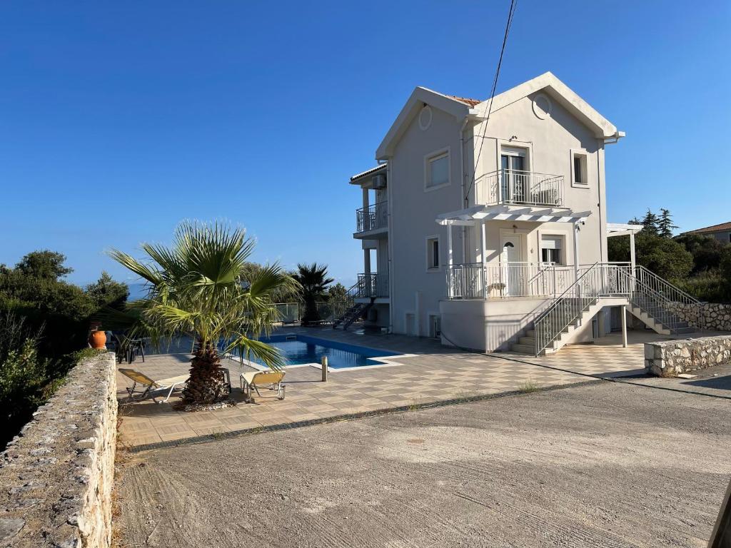 ein weißes Haus mit einem Pool und einer Palme in der Unterkunft Villa Evangelia in Karavádhos