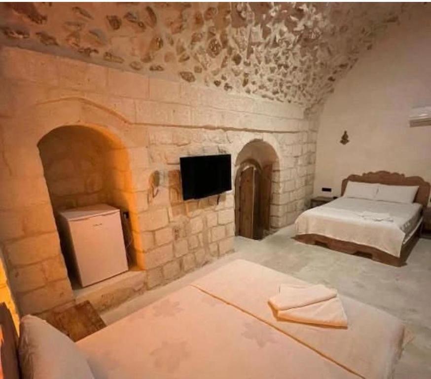 een slaapkamer met een bed en een tv in een stenen muur bij Beylerbeyi Butik Otel in Midyat
