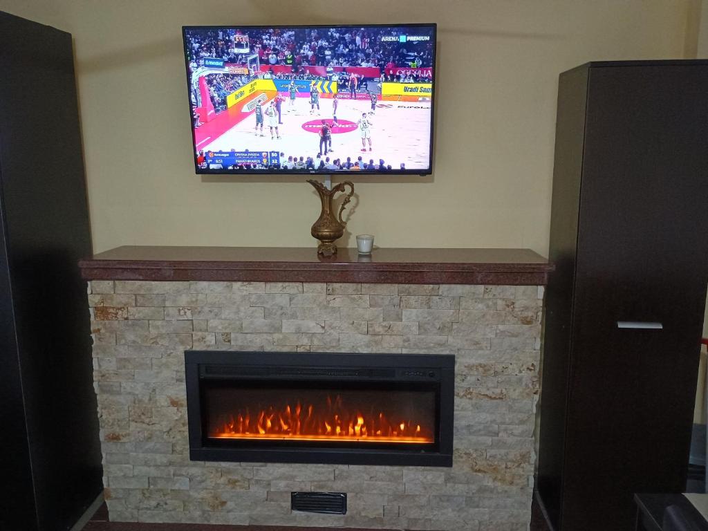 Un televisor encima de una chimenea con un televisor encima. en APARTMANSKI SMEŠTAJ SOLARIS kod Aqua Parka Lux Apartman LAZAR, en Soko Banja