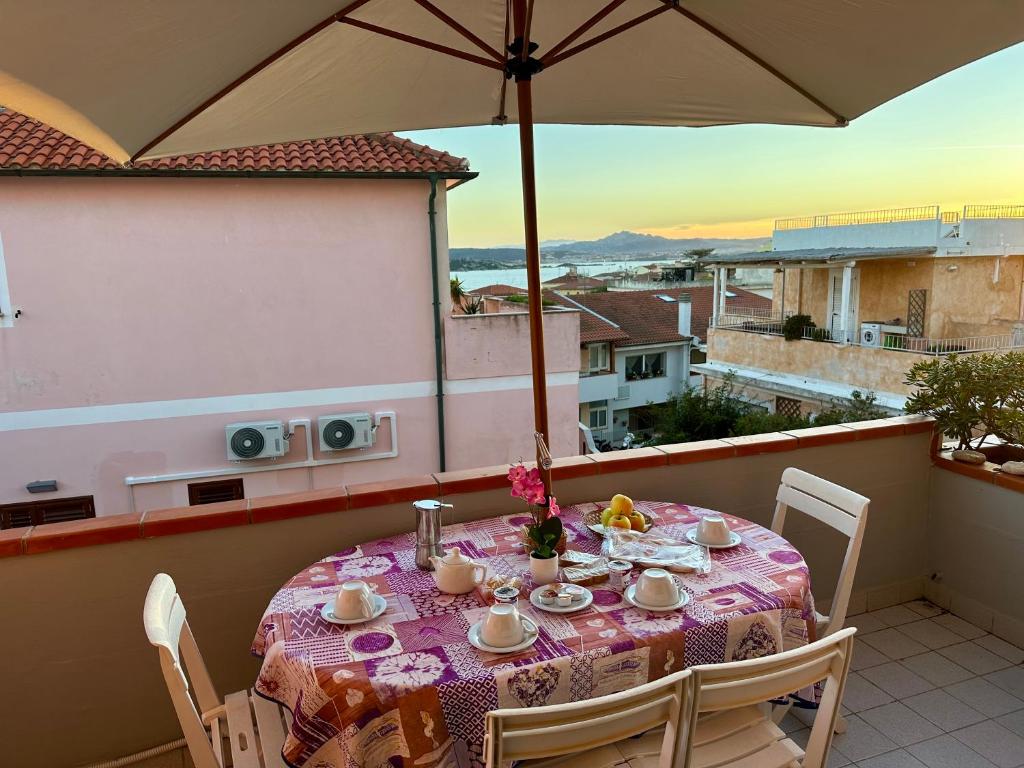 einen Tisch auf einem Balkon mit Sonnenschirm in der Unterkunft SPARGI Apartment in La Maddalena
