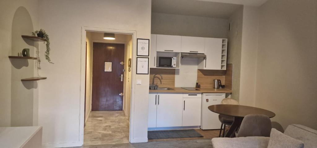 a small kitchen with white cabinets and a table at Le Cocon de la Prom in Nice
