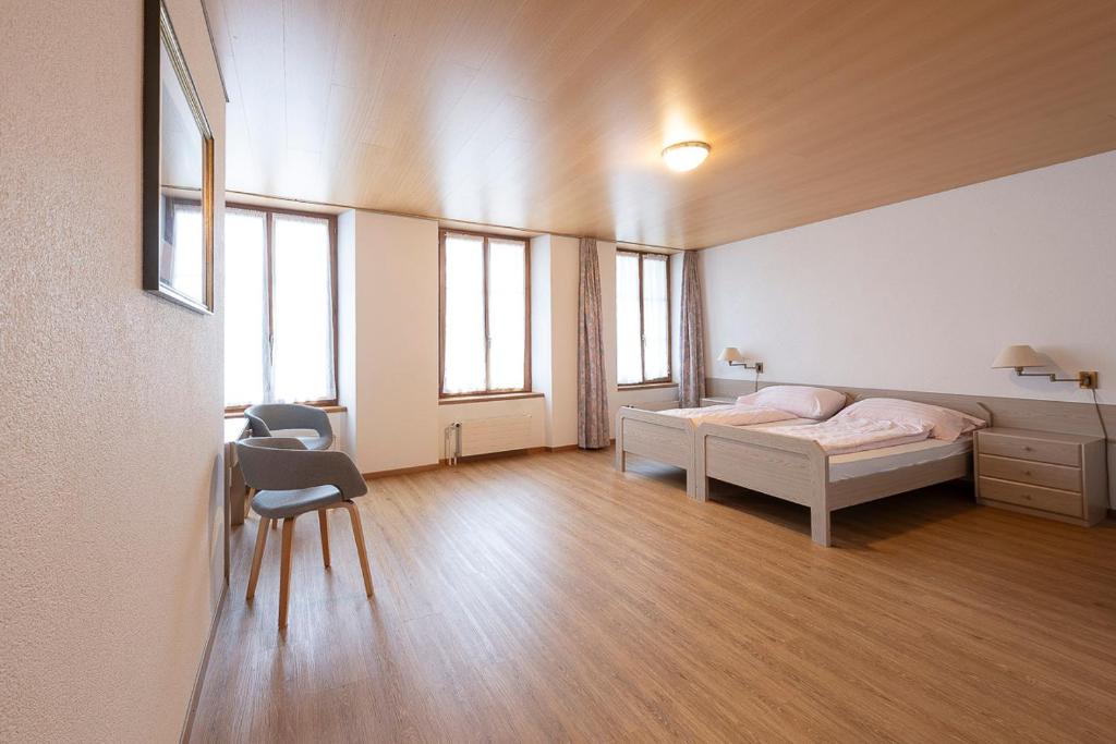 a bedroom with a bed and a desk and some windows at Gasthof zur alten Post in Büren an der Aare