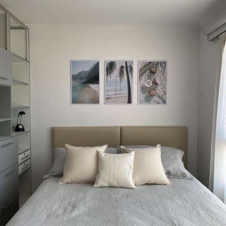a bedroom with a bed with three pictures on the wall at Aire de Mar II - Alojamientos Necochea in Necochea