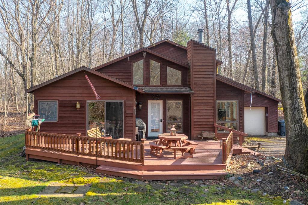a log cabin in the woods with a wooden deck at Charming 3 bed 2 bath home near dunes, beach and trails in South Haven