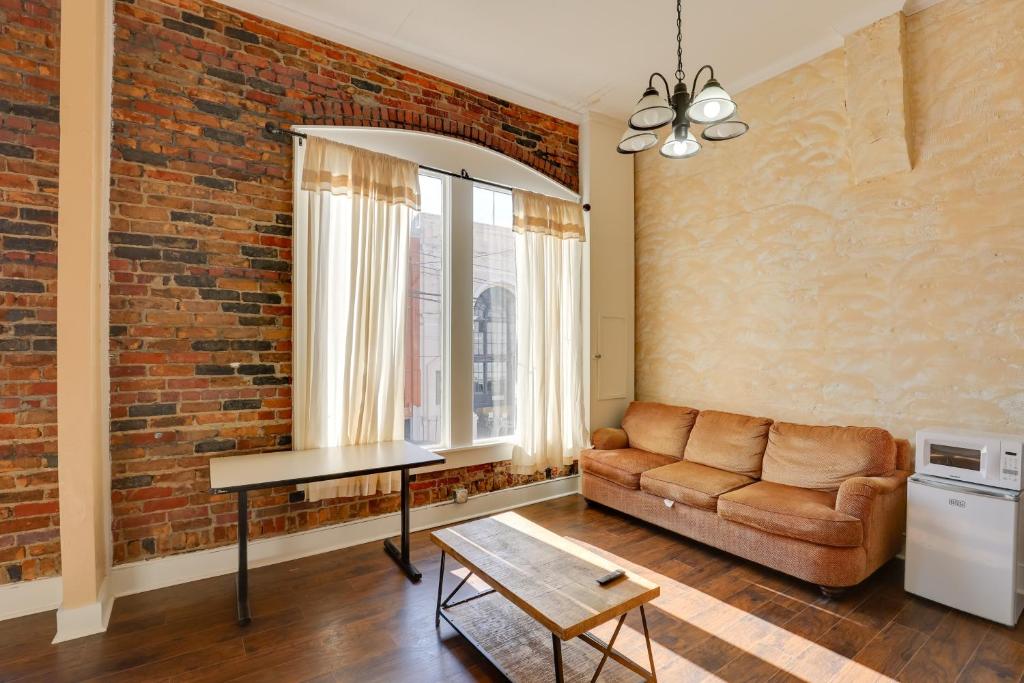 a living room with a couch and a brick wall at Pet-Friendly Studio in Historic Dtwn Marshall! in Marshall