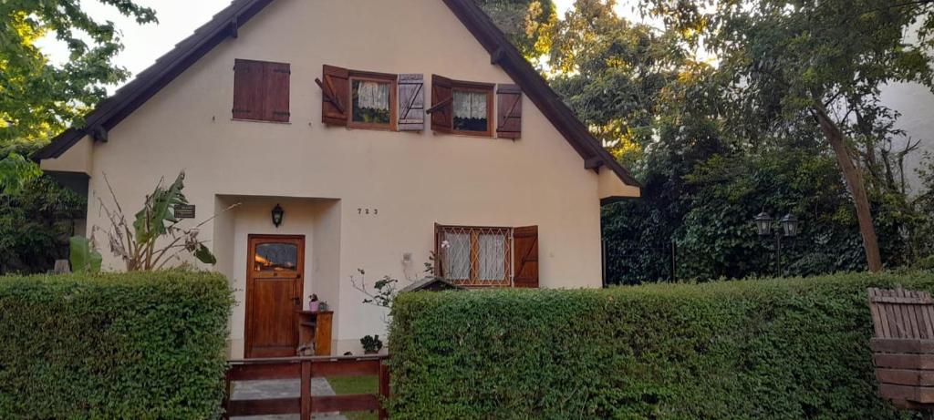 una casa blanca con ventanas y un seto en Alquilo casa en Villa Gesell por temporada, en Villa Gesell