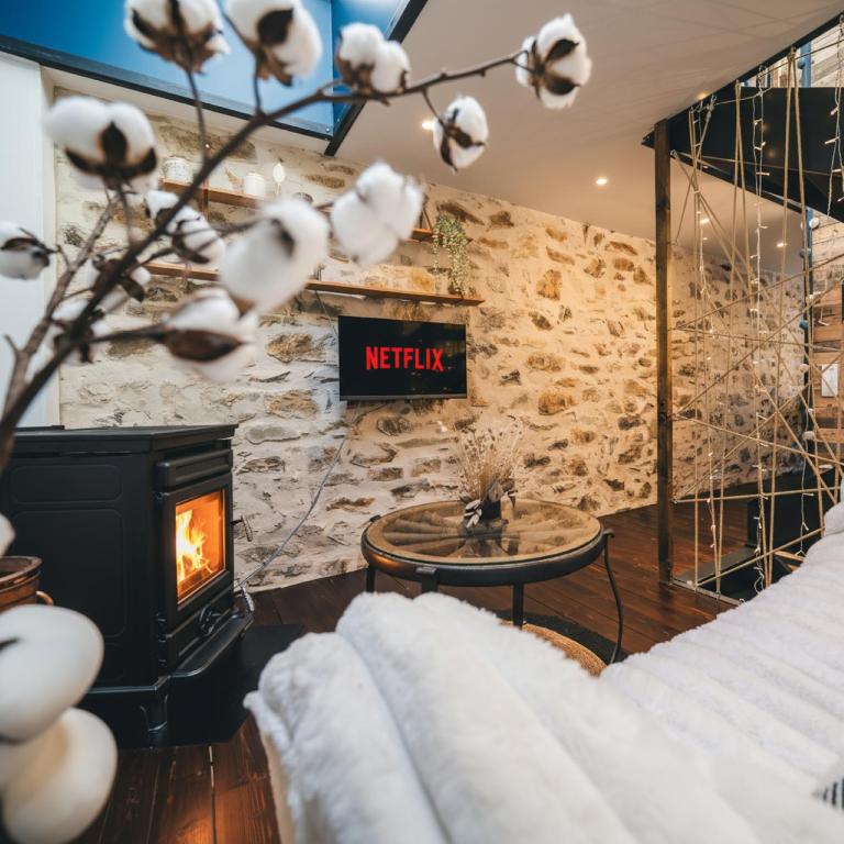 a living room with a stone wall and a fireplace at L'Atelier - Gîte chaleureux et relaxant in Saint-Hubert
