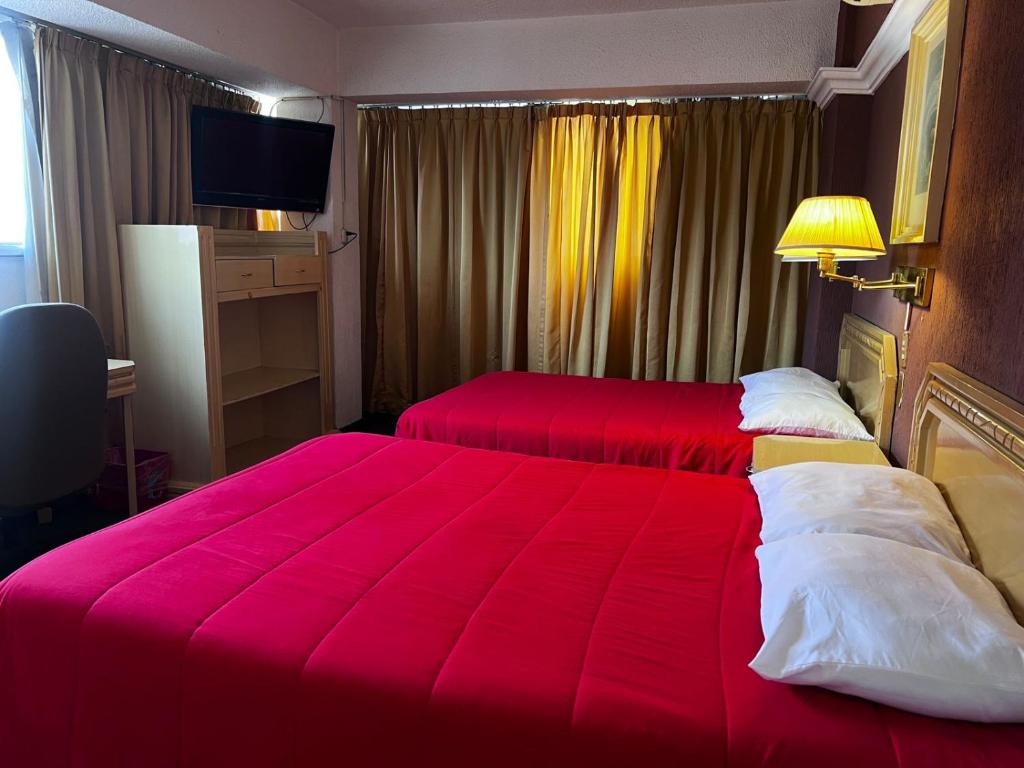 a hotel room with two beds with red sheets at Hotel María Teresa in Salamanca