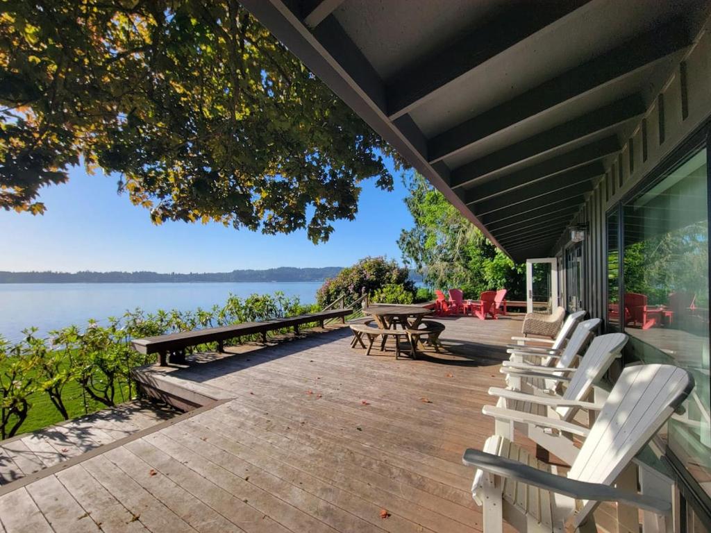 a porch with chairs and tables and a view of the water at Enetai Beach House with dock and Hot Tub in Point White