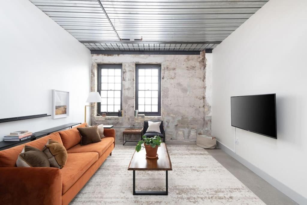 Una sala de estar con un sofá y un televisor de pantalla plana. en Chic Double Queen Apt Walking Distance to Fiserv, en Milwaukee