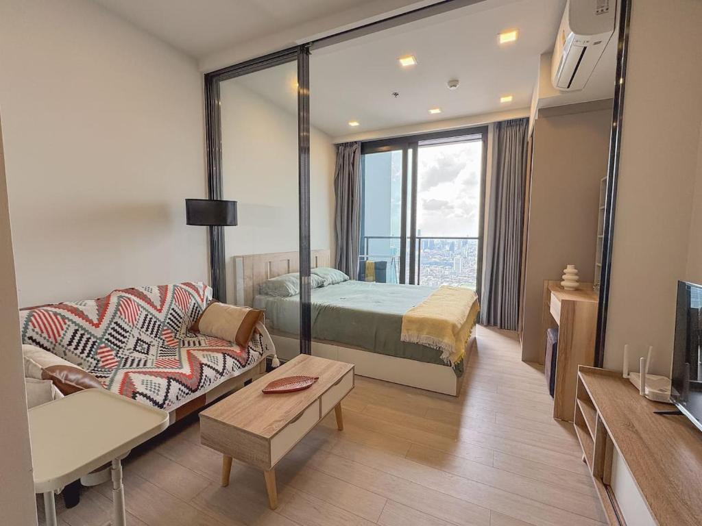 a hotel room with a bed and a couch at Near Central Rama 9 with Balcony, Pool, Gym & 5m to MRT in Bangkok