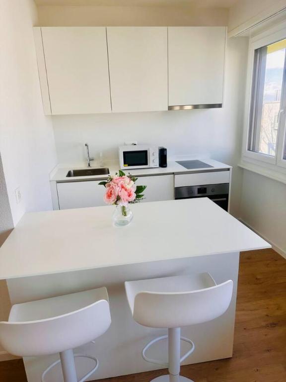 a white kitchen with a table and two chairs at The Minimalist free Parking in Lausanne