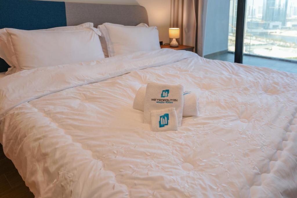 ein weißes Bett mit zwei Handtuchboxen darauf in der Unterkunft 1 BR in Maryah Island with balcony in Abu Dhabi