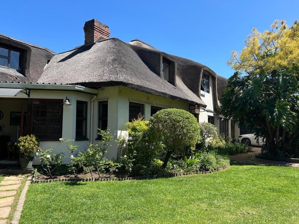 una casa vieja con techo de paja y un patio en Shire Lodge, en Ciudad del Cabo
