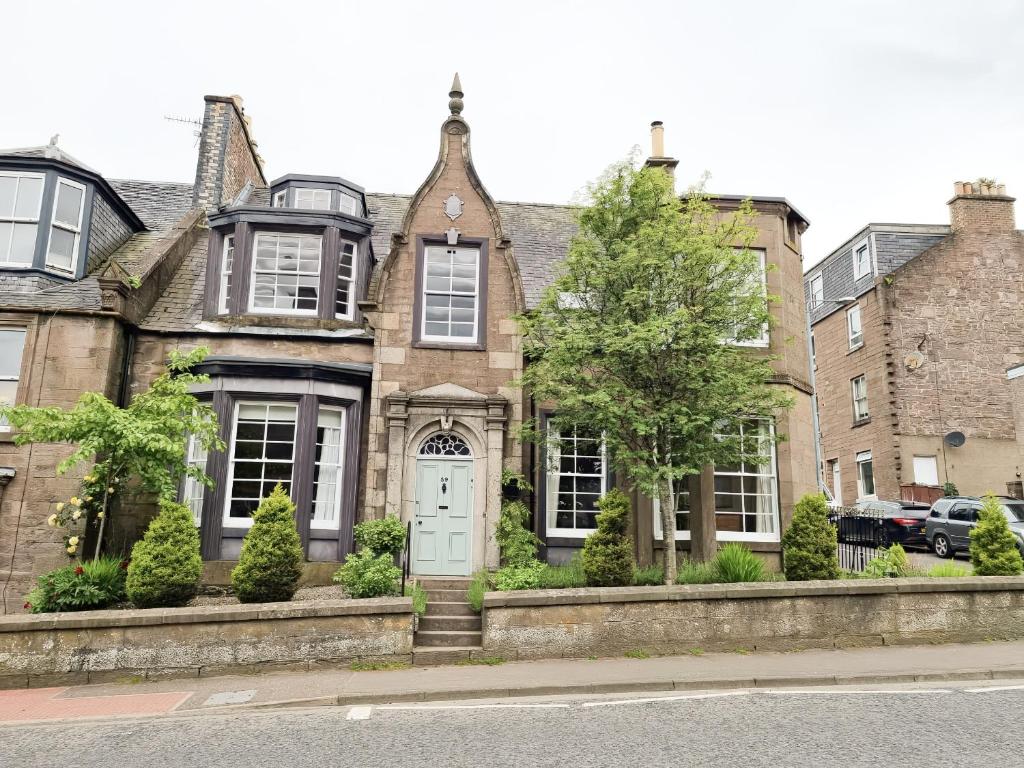 an old brick house with a white door at Rowan Tree House in Brechin