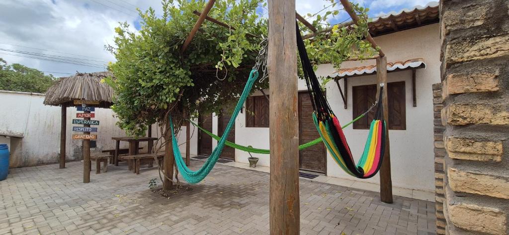 a house with hammocks hanging from a tree at Pousada Coró in São Miguel do Gostoso