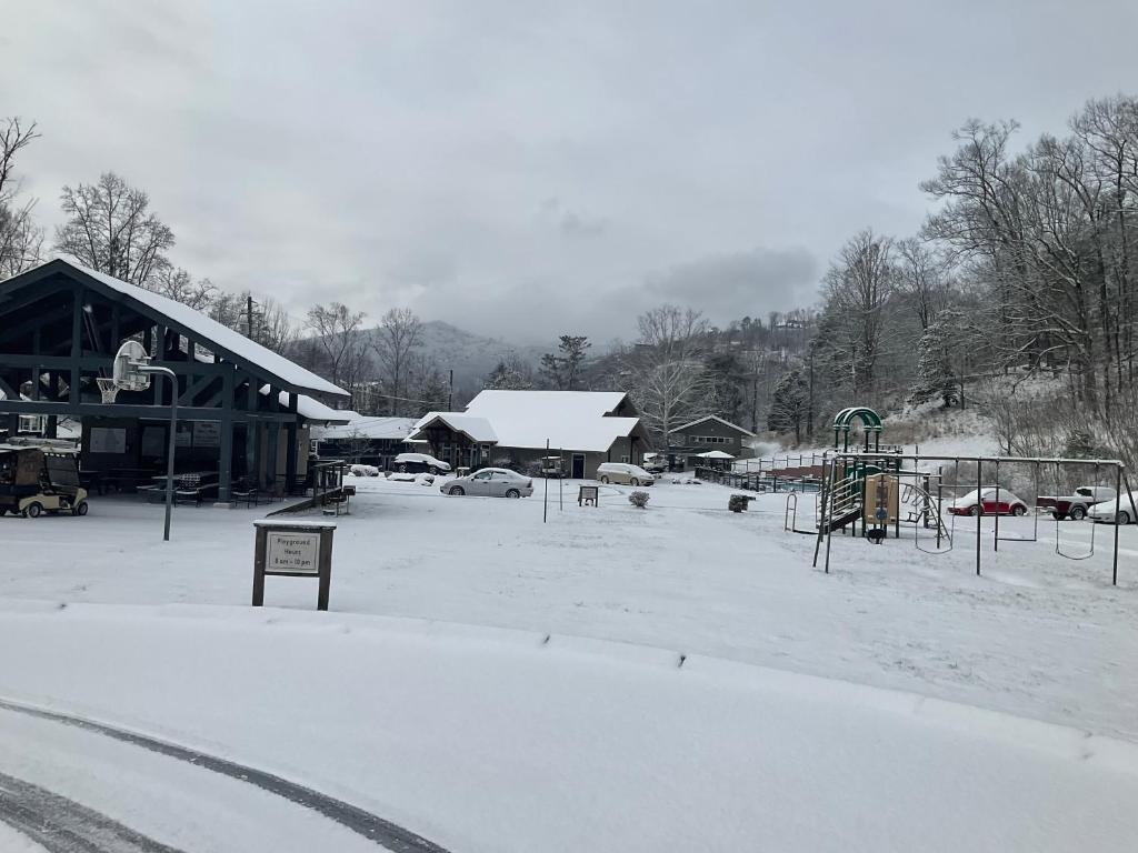 un parc recouvert de neige avec une aire de jeux dans l'établissement Carr's Northside Hotel and Cottages, à Gatlinburg