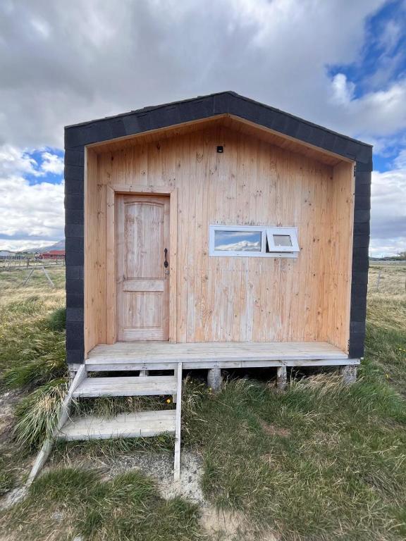 a wooden outhouse with a door in a field at Tiny House Camino 3 in Puerto Natales