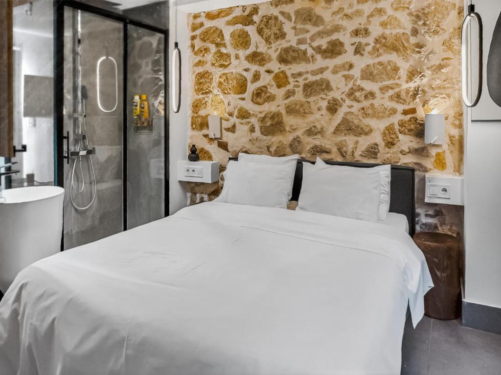 a bedroom with a white bed and a stone wall at Ρομαντική απόδραση με Χαμάμ in Athens