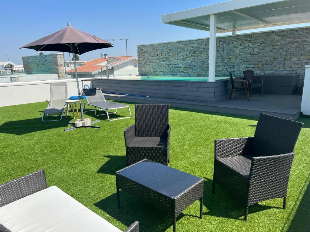 un groupe de chaises, une table et un parasol dans l'établissement Elegante appartamento con piscina privata, à Peschiera del Garda