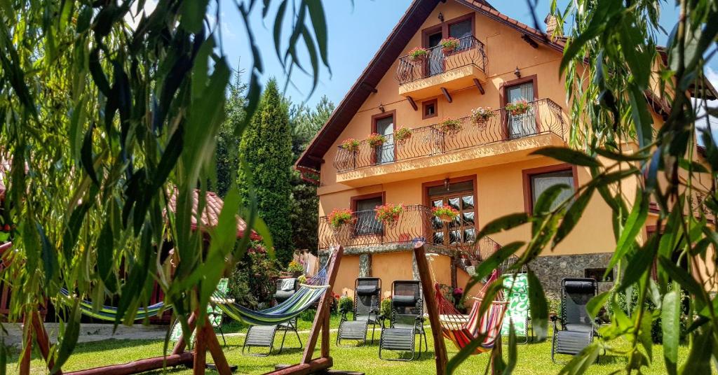 a building with balconies and chairs in a yard at Casa Florina in Predeluţ