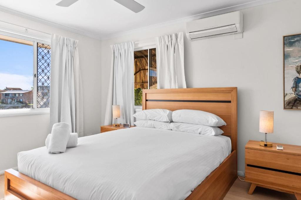 a bedroom with a bed with white sheets and a window at Family-Friendly Flat with Balcony Views in Mooloolaba