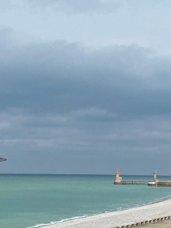 a view of the ocean with a pier in the background at Gîte Les pieds dans l eau à Fécamp avec pleine vue mer in Fécamp
