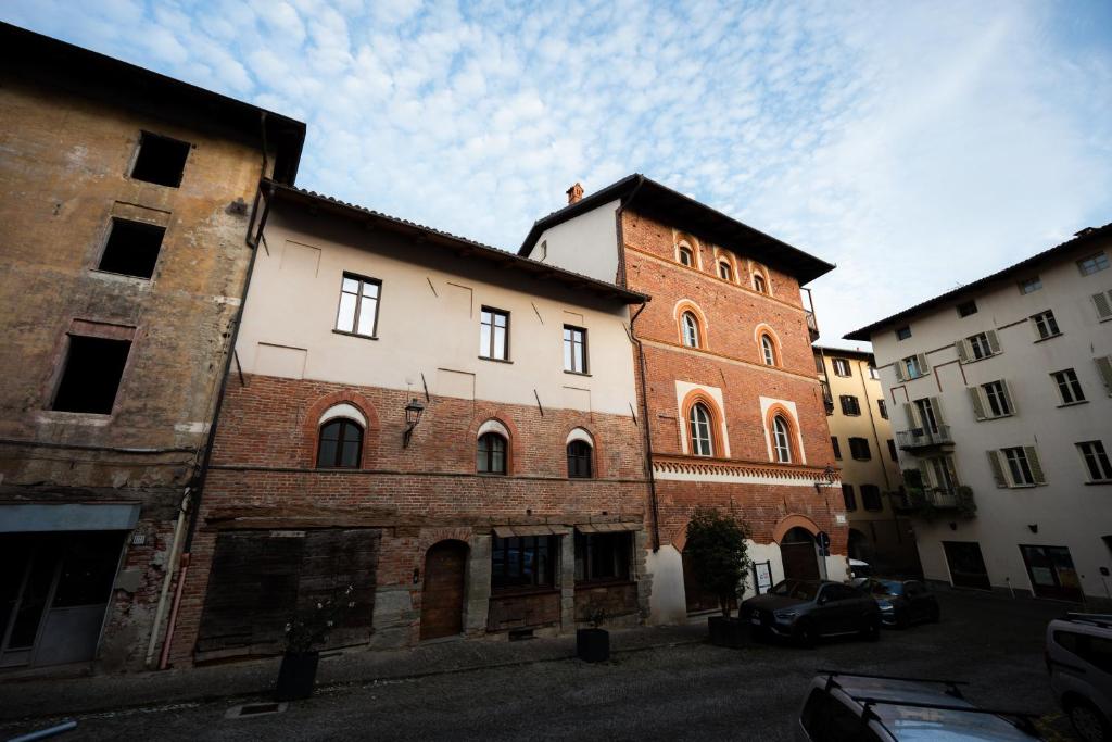 an old brick building with a tower in a parking lot at Domus Acaja in Pinerolo