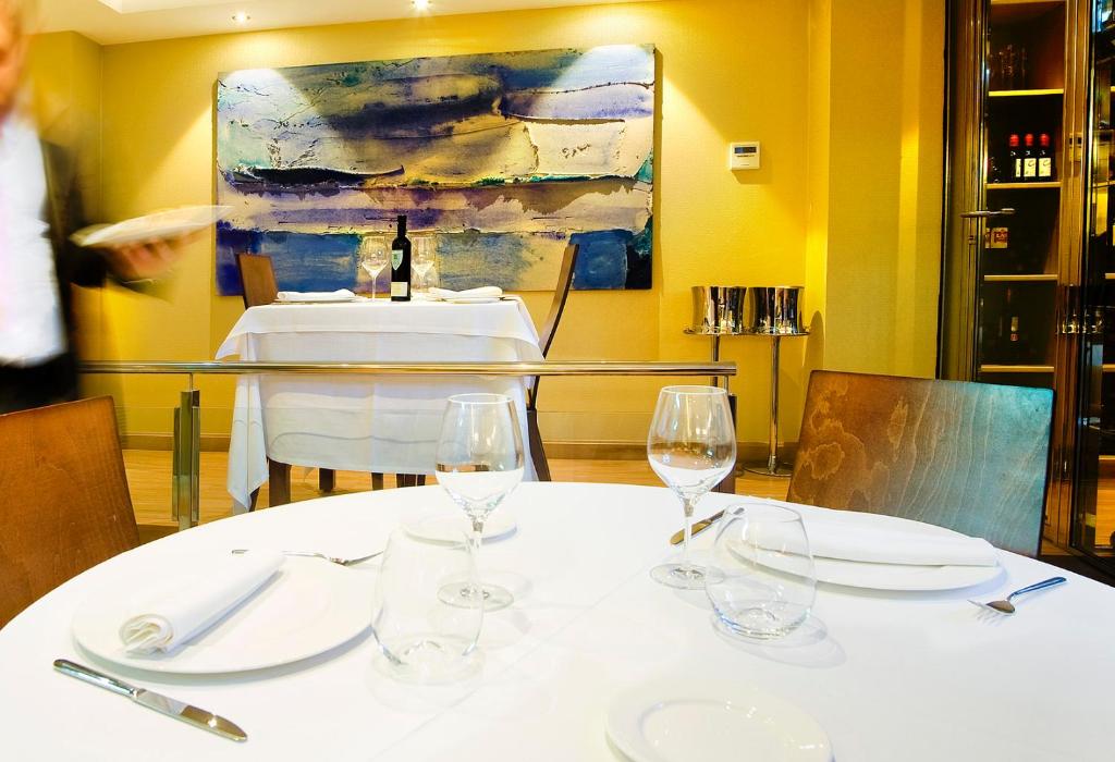 a table with wine glasses on it with a painting at Hotel Campoamor in Oviedo
