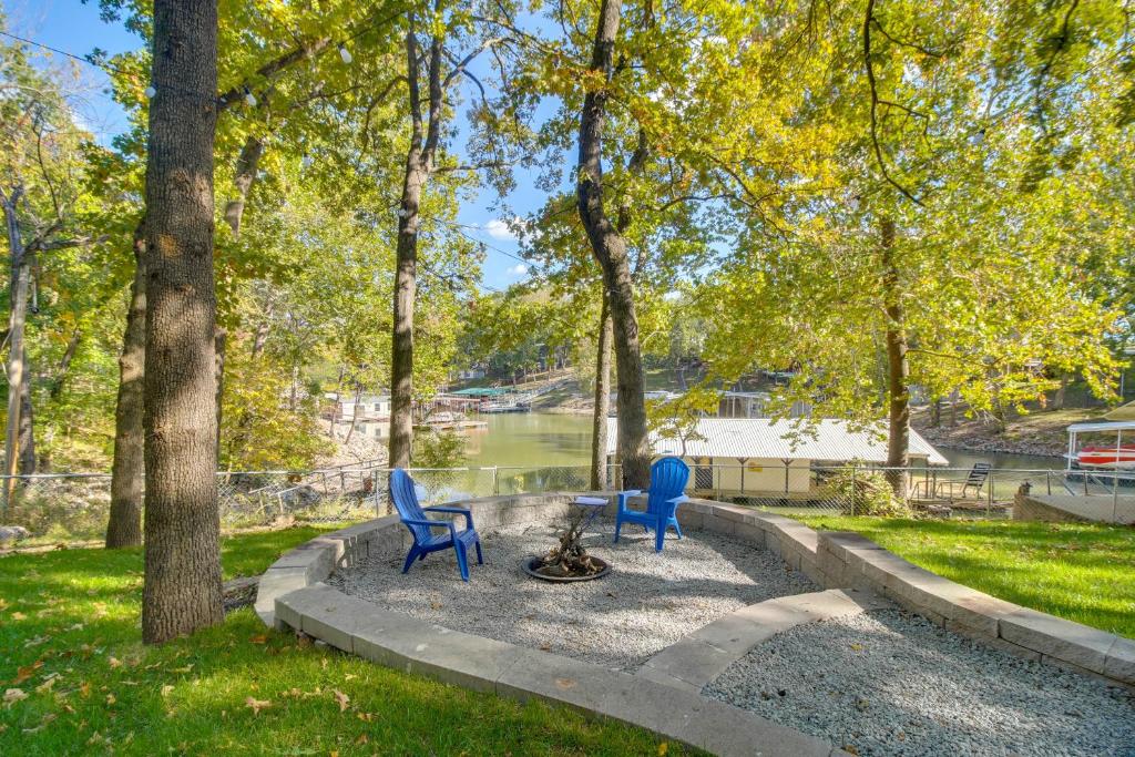 Monkey IslandGame Room, Dock and Hot Tub Grand Lake Getaway的公园里，靠近一条河，摆放着两把蓝色的椅子。