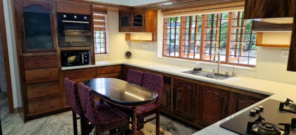 a kitchen with wooden cabinets and a table and chairs at Chakos Homestay in Kaduturutti