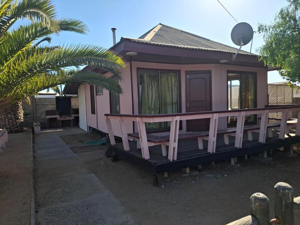 a small pink house with a porch and a palm tree at Cabaña para 6 personas cerca de la playa in Coquimbo