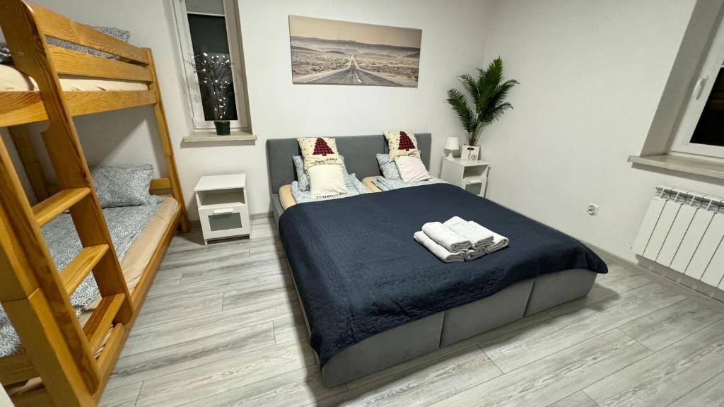 een slaapkamer met een bed met een blauwe deken en een ladder bij Apartamenty ZATOR20 2 min od Energylandii in Zator