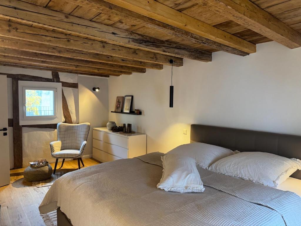 a bedroom with a large bed and a chair at EifelQuartier L9 in Schleiden