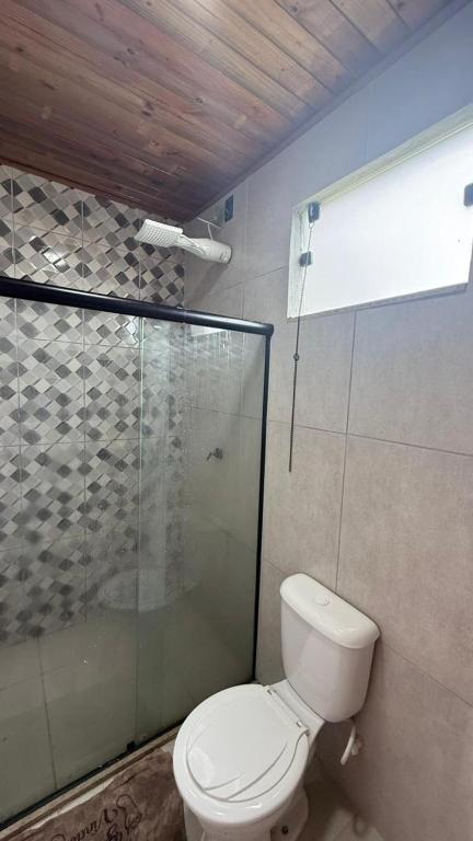 a bathroom with a toilet and a glass shower at Recanto das Guerreiras in Marau