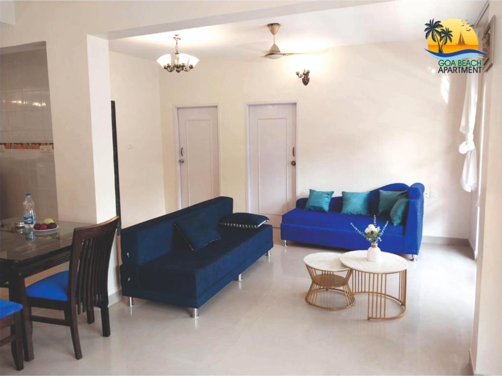 a living room with a blue couch and a table at Goa Beach Apartment in Colva