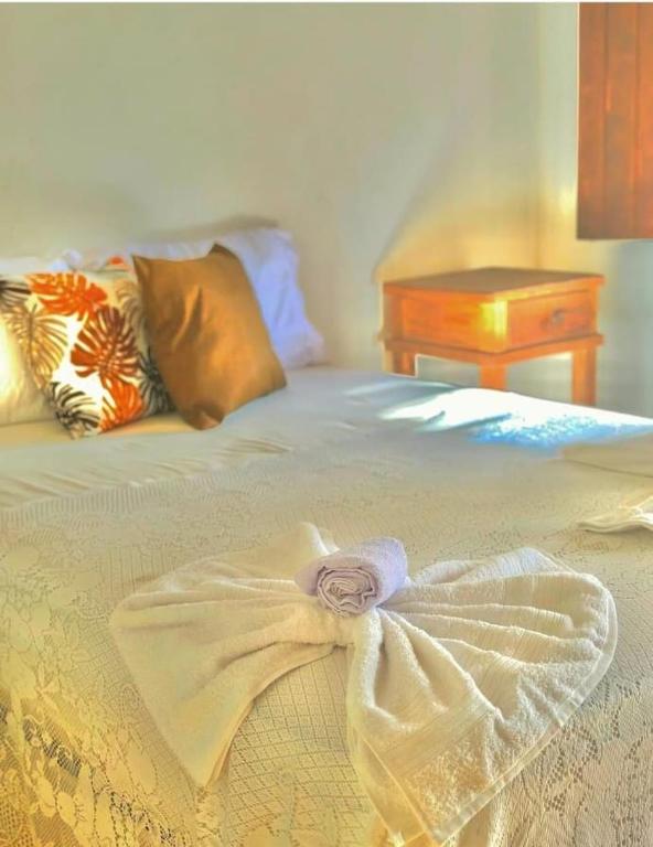 a bed with a dress on it with a table at Pousada Eloy Beach in Trancoso