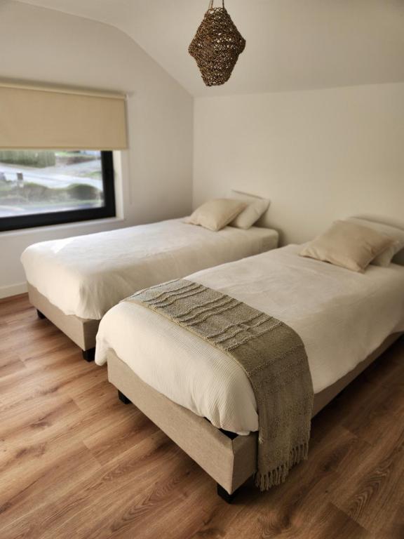 シント・トロイデンにあるVerliefd in Brustemのウッドフロアのベッドルーム(窓付)のベッド2台