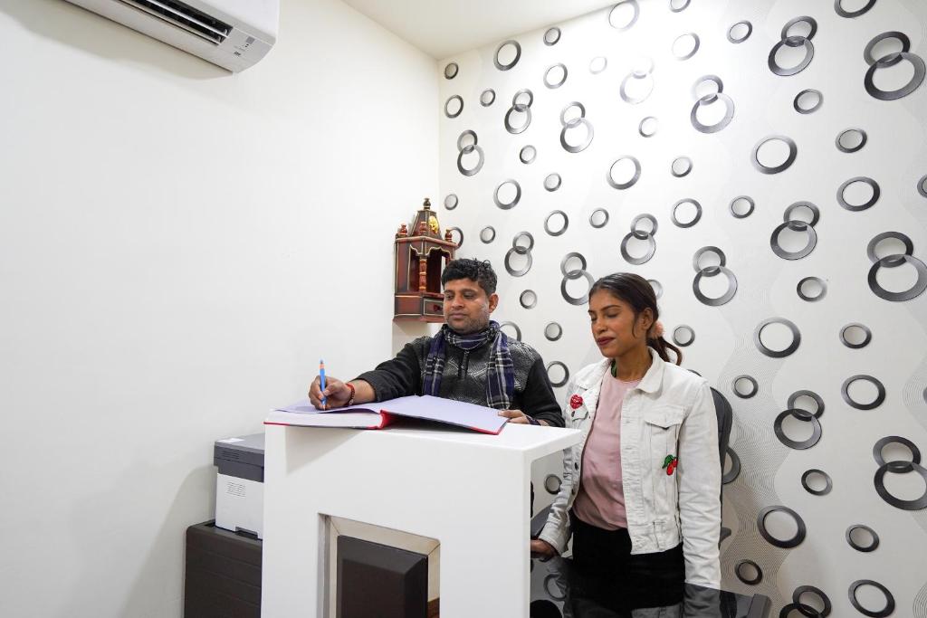 un hombre y una mujer de pie en un escritorio en Hotel O Mannat, en Nueva Delhi